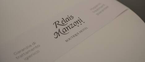 A toilet with a label that reads "Relais Manzoni" and "Guarantee di trattamento igienico."