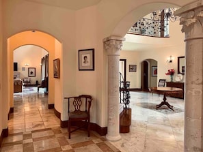 Eine großzügige Lobby mit Schachbrettmuster-Boden, einer imposanten Treppe und klassischen Säulen.