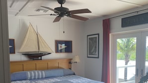 A bedroom with a bed, a ceiling fan, a sailboat model, and a view of the outside. - Beautiful Bokeelia!!!! Fishing dream! Bring your boat and your dog (Bokeelia)