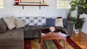 A living room with a gray sectional sofa, a wooden coffee table, a colorful rug, a map on the wall, and a sailboat model. - Beautiful Bokeelia!!!! Fishing dream! Bring your boat and your dog (Bokeelia)