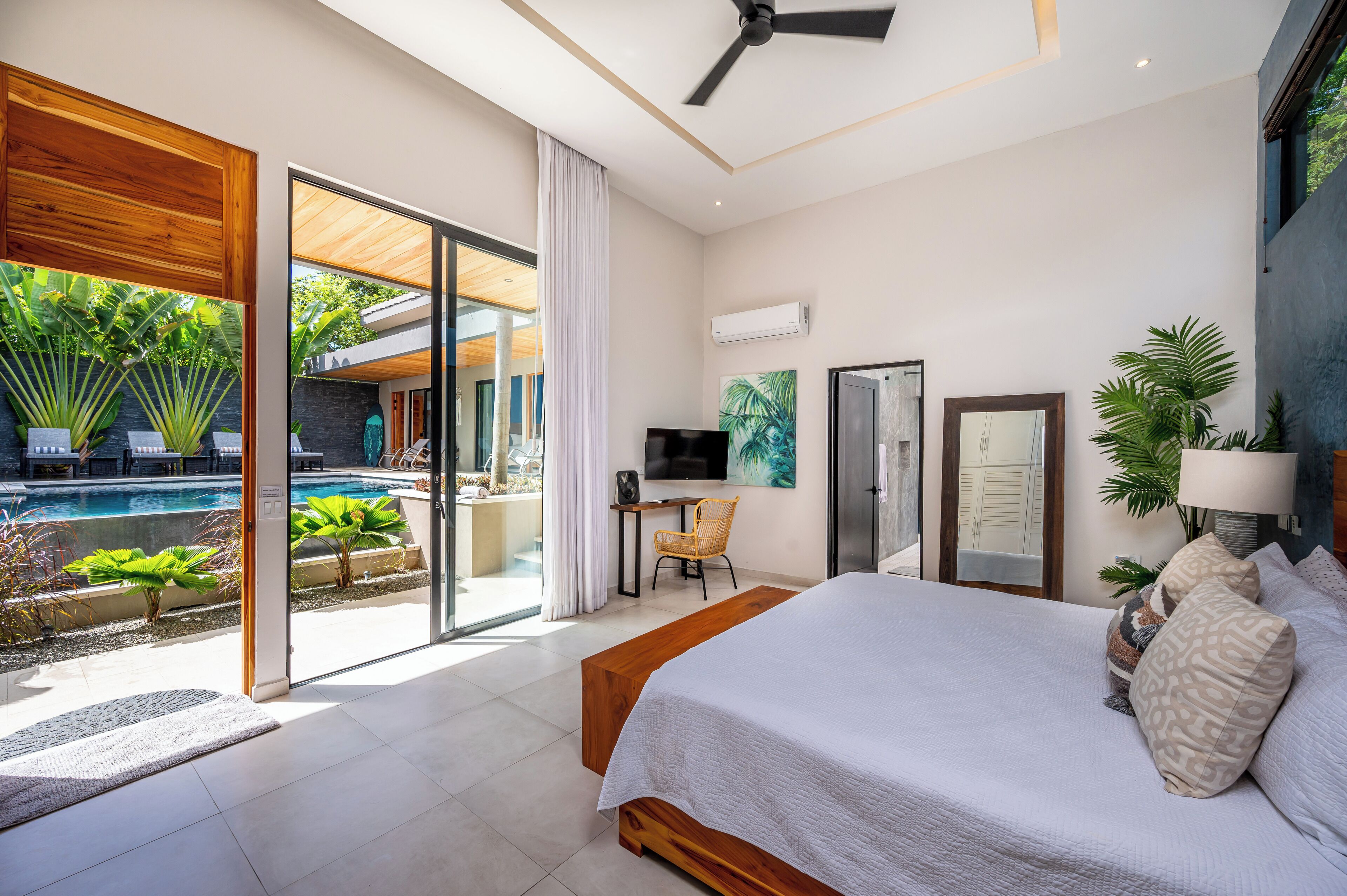 Une chambre moderne avec un grand lit, un bureau et une vue sur une piscine.