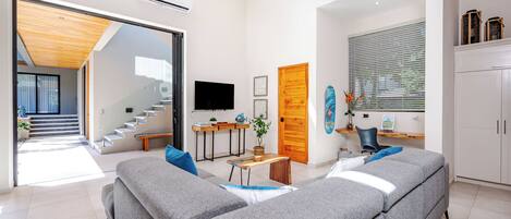 Una sala de estar moderna con un sofá seccional gris, una mesa de centro de madera y un televisor sobre un mueble.