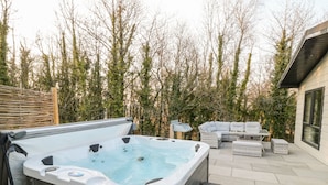 A hot tub with steps, surrounded by outdoor furniture and a wooden fence. - Mayflower (Lifton)