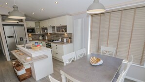 A modern kitchen with white cabinetry, a central island, and pendant lighting.