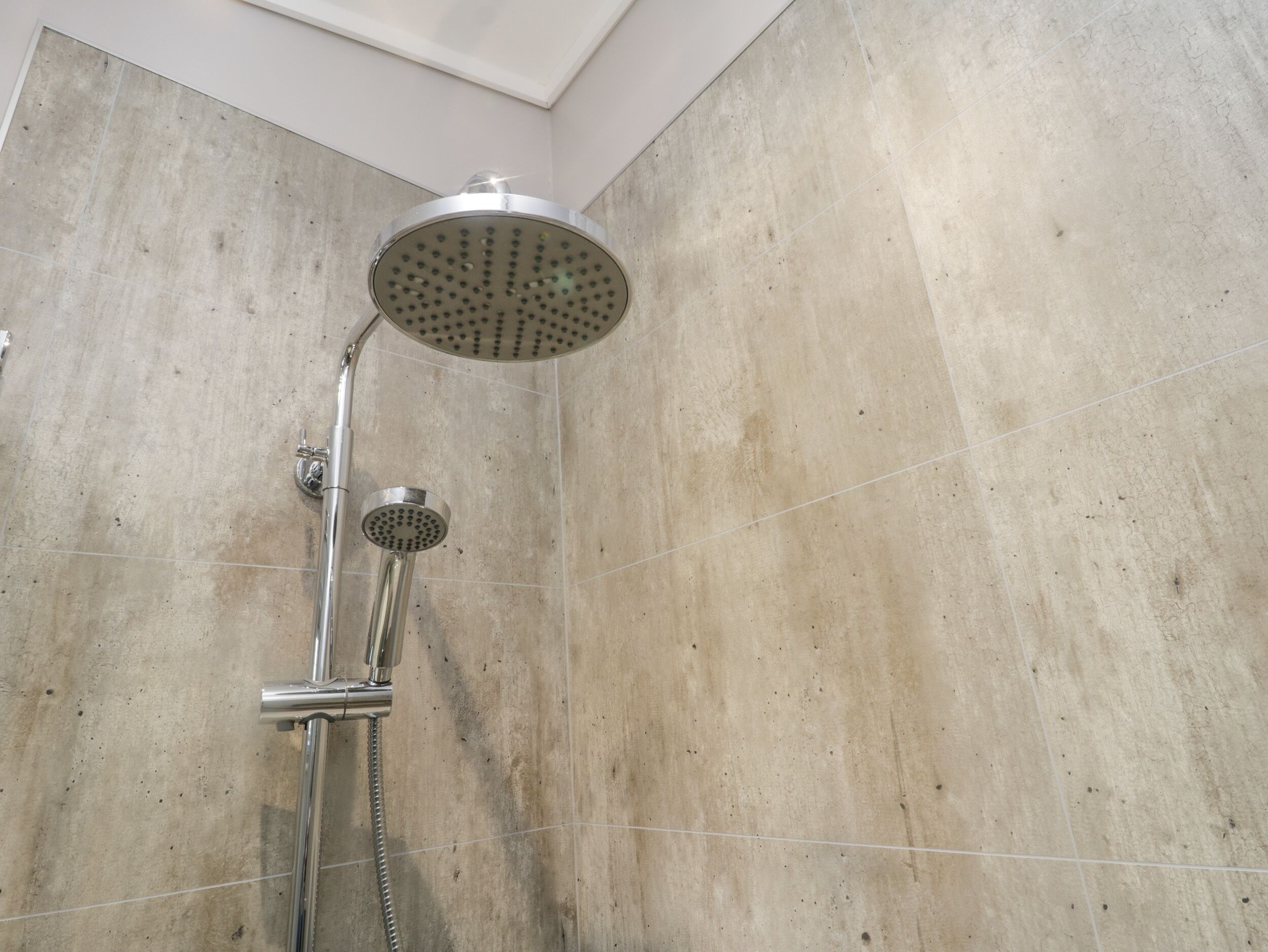 A shower with a round head and a handheld showerhead.