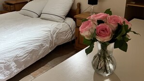 A bedroom with a bed, bedside table, lamp, and a vase with flowers. - Gîte 2/4 people with swimming pool and view of the Orb valley (Cessenon sur Orb)