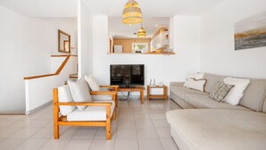 A living room with a TV, wooden furniture, a sofa, and a staircase.