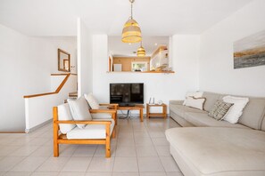 A living room with a TV, wooden furniture, a sofa, and a staircase.
