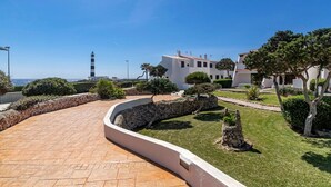 Una propiedad costera con un sendero pavimentado, muros de piedra y céspedes bien cuidados.