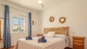 A bedroom with a bed, two nightstands, a window with curtains, and a ceiling fan. - VILLA MICA  Cheerful 3 bedroom villa with pool and A/C (Son Carrió)