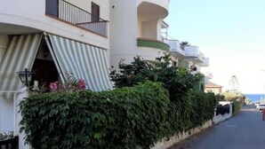 A building with a white facade, green trim, and a balcony with a metal railing. - Emily Home (Giardini Naxos)