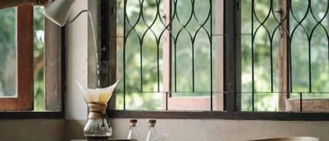 A corner room with a table, a chair, and a window with metal bars.