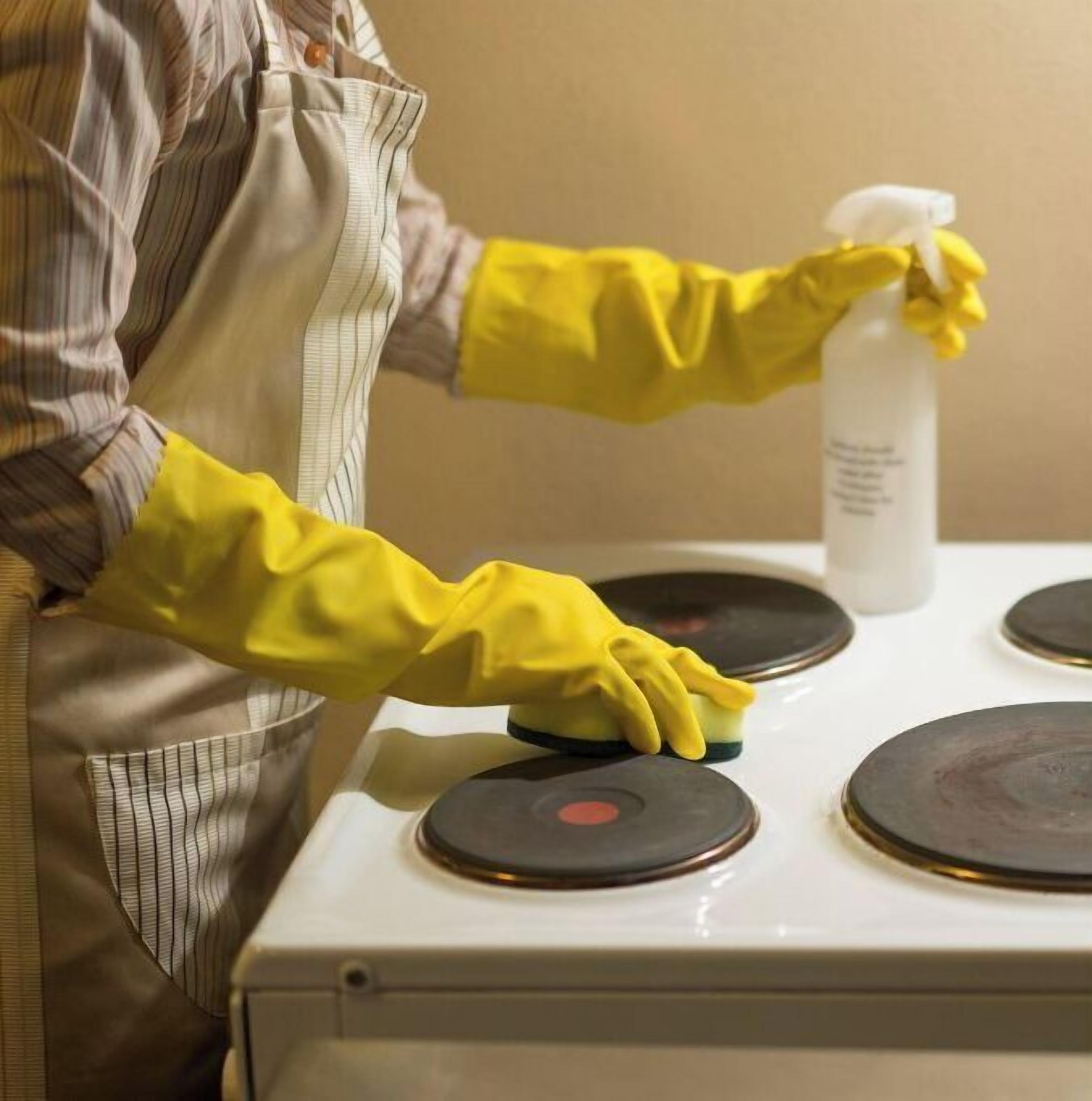 Une personne nettoie une cuisinière à l’aide d’un vaporisateur et d’un chiffon.
