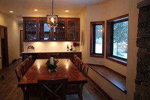 Un comedor con una mesa y sillas de madera, una cocina con armarios de madera y una pared de piedra.