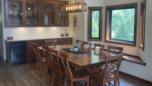 Eine geräumige Küche mit Holzausstattung, einem Esstisch mit Stühlen und großen Fenstern für natürliches Licht.