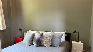 Een slaapkamer met een bed, een nachtkastje, een rode kast en een plafondventilator.