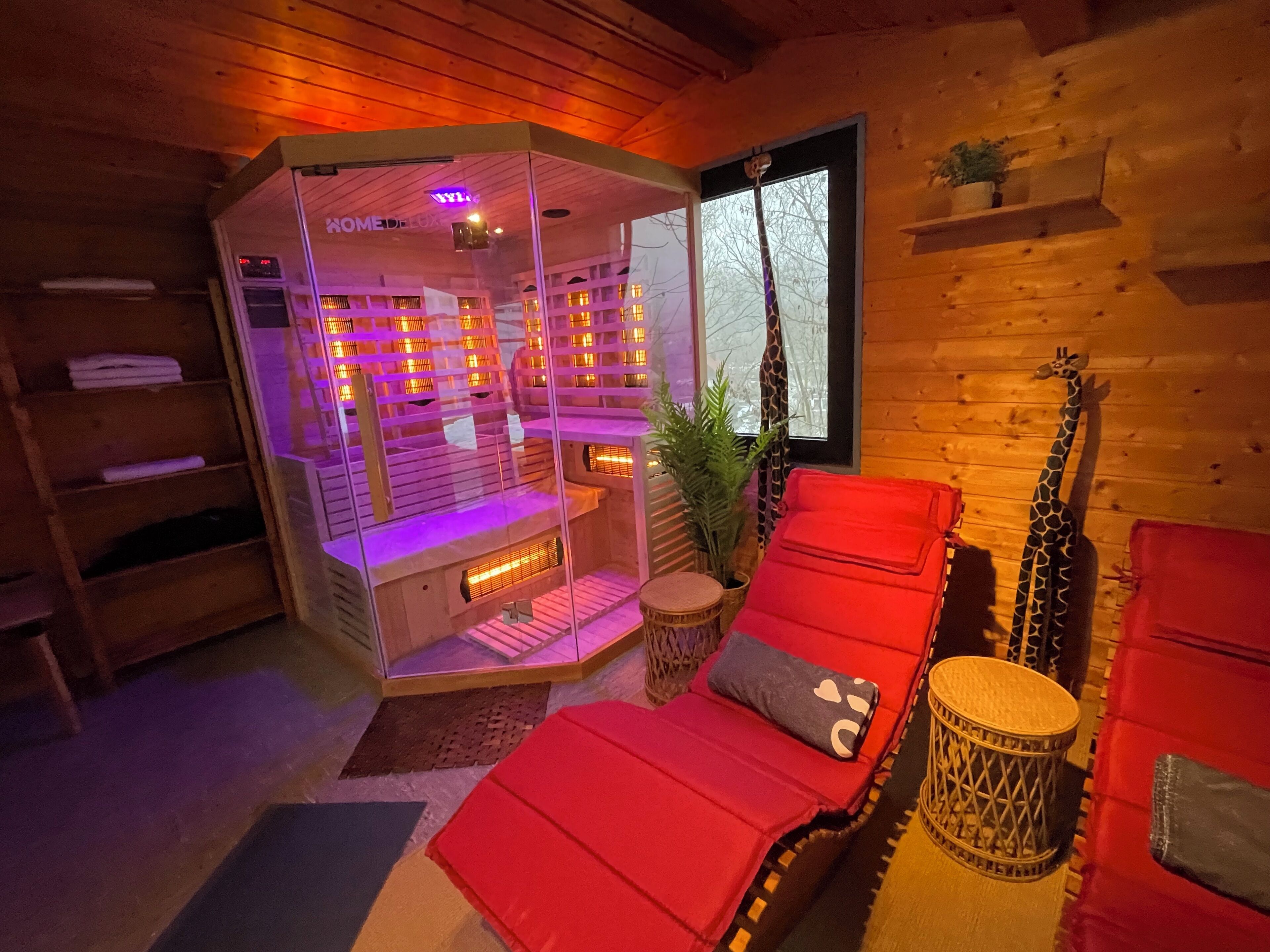 A room with a massage chair, a wooden wall, a window, and a giraffe statue.