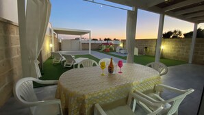 Une terrasse extérieure avec une table ronde, des chaises blanches et une nappe.