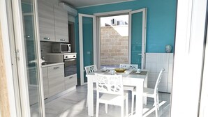 Une cuisine moderne avec des meubles blancs, un four à micro-ondes et un coin repas comprenant des chaises et une table, le tout dans des tons blancs.