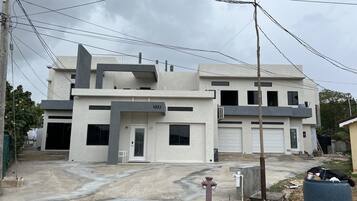 A modern two-story building with a flat roof, a garage, and a visible number "332".