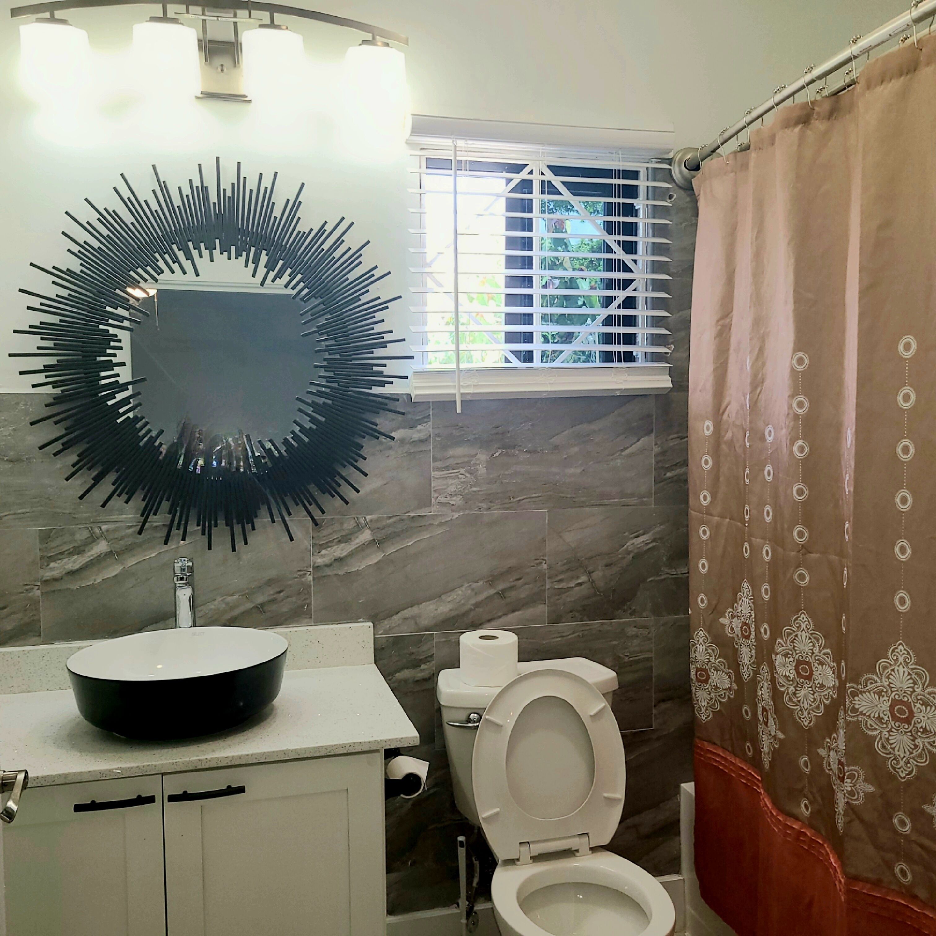 A bathroom with a modern sink, a toilet, and a shower curtain.