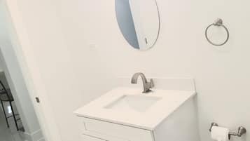 Un bagno con un mobile lavabo bianco, un lavandino, uno specchio e un portasciugamani.