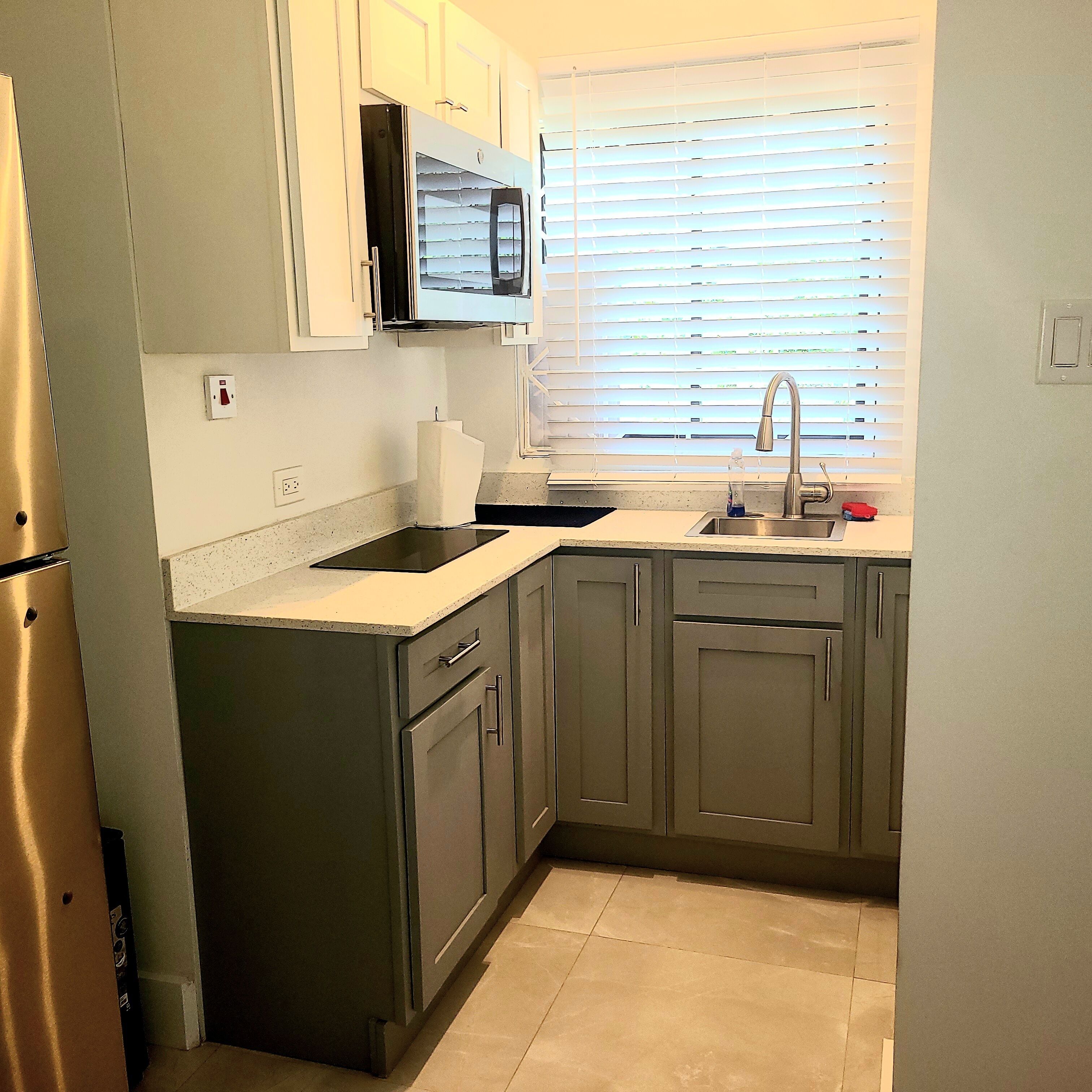 A kitchen with a stainless steel refrigerator, a microwave, a sink, and cabinets.