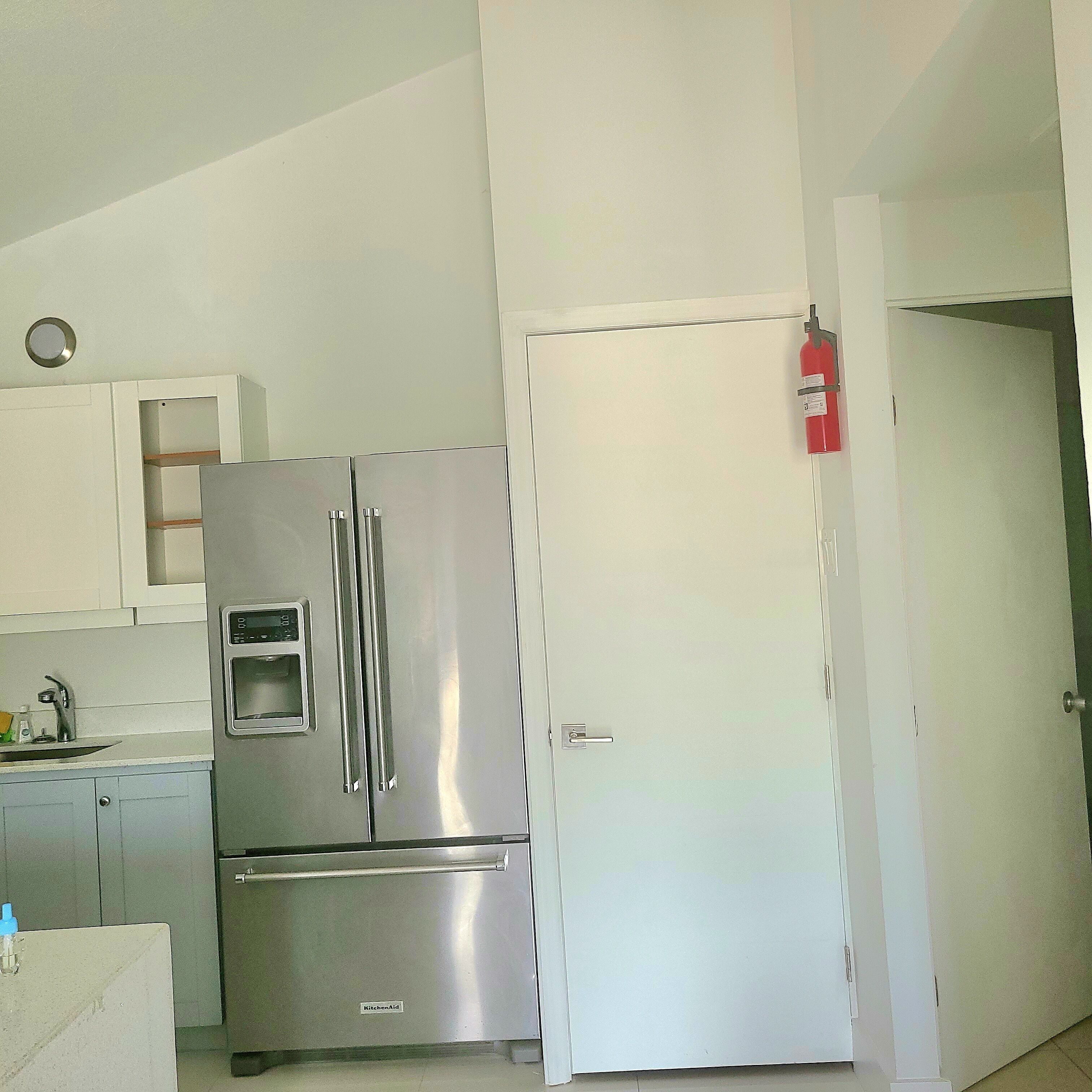 A compact kitchen with a stainless steel refrigerator and a white door.