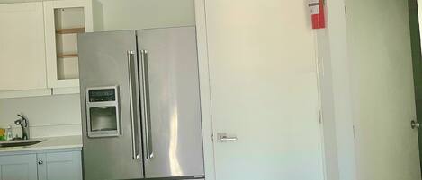 A compact kitchen with a stainless steel refrigerator and a white door.