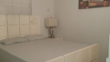 A bedroom with a bed, a nightstand, a lamp, and a painting on the wall.