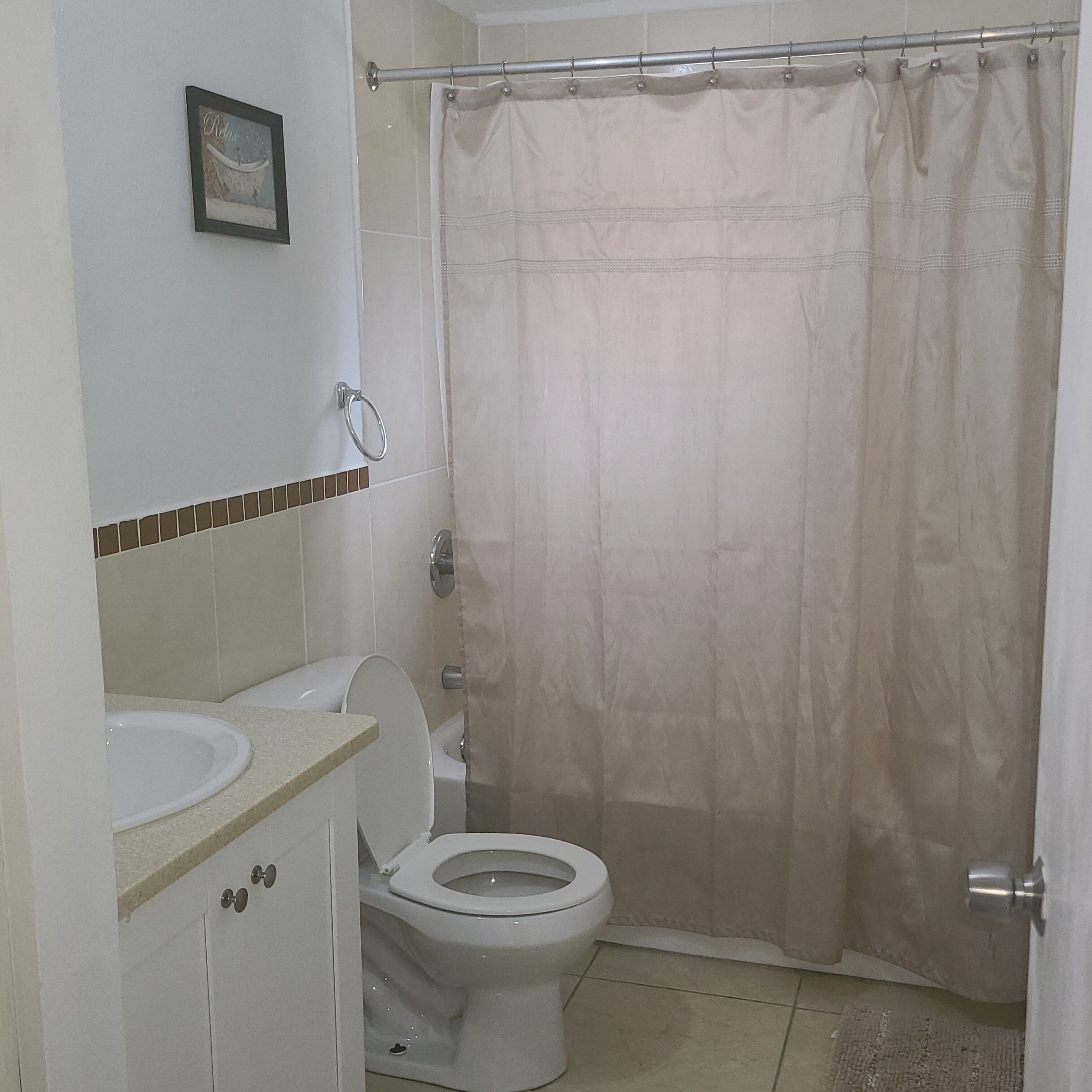 A bathroom with a toilet, sink, and a shower curtain.