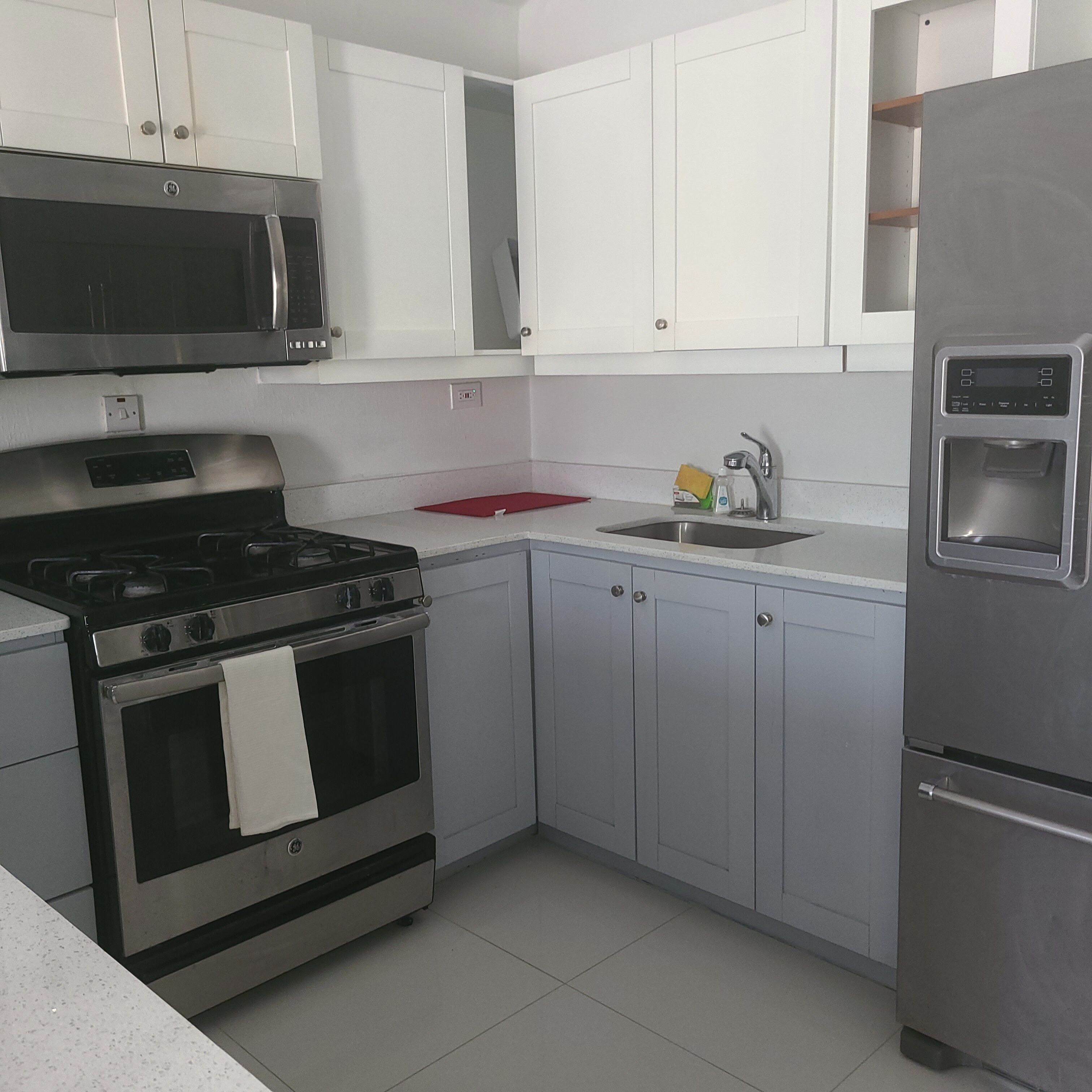A kitchen with white cabinets, stainless steel appliances, and a red cutting board.