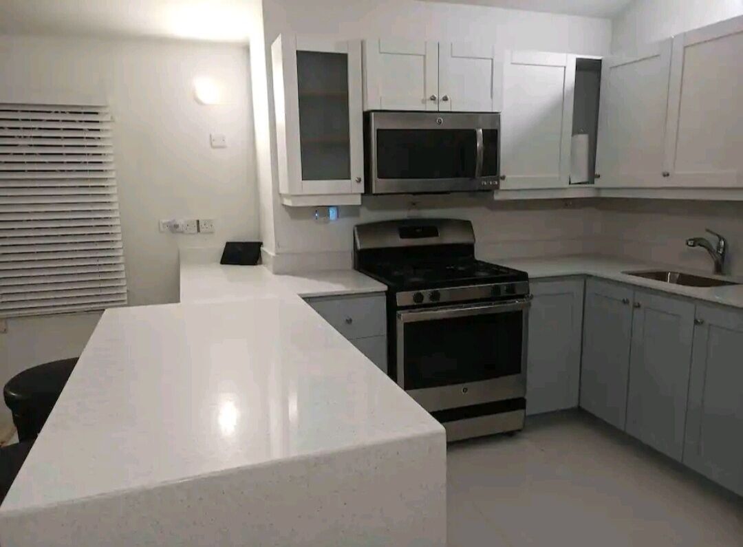 Une cuisine moderne avec des meubles blancs, un four à micro-ondes encastré, une cuisinière et un évier.