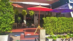 Ein Hostel mit Außenbereich, Sonnenschirmen und einem Pool.
