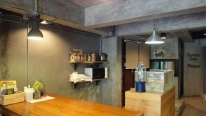 L’intérieur d’un café chaleureux et accueillant, avec un comptoir en bois, des étagères remplies de produits liés au café et un panneau indiquant « Réservé aux clients ».