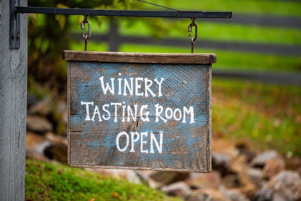 A wooden sign indicating a winery tasting room is open.