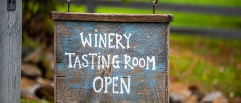 A wooden sign indicating a winery tasting room is open.