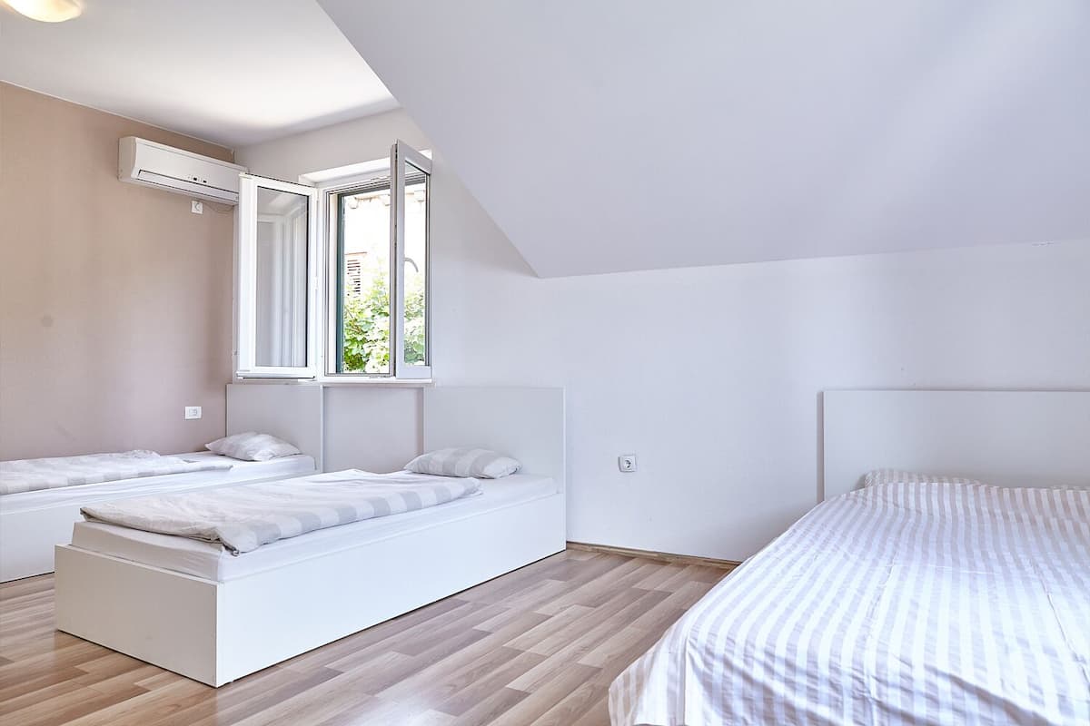 Una camera da letto moderna con due letti singoli, un'ampia finestra e un condizionatore.