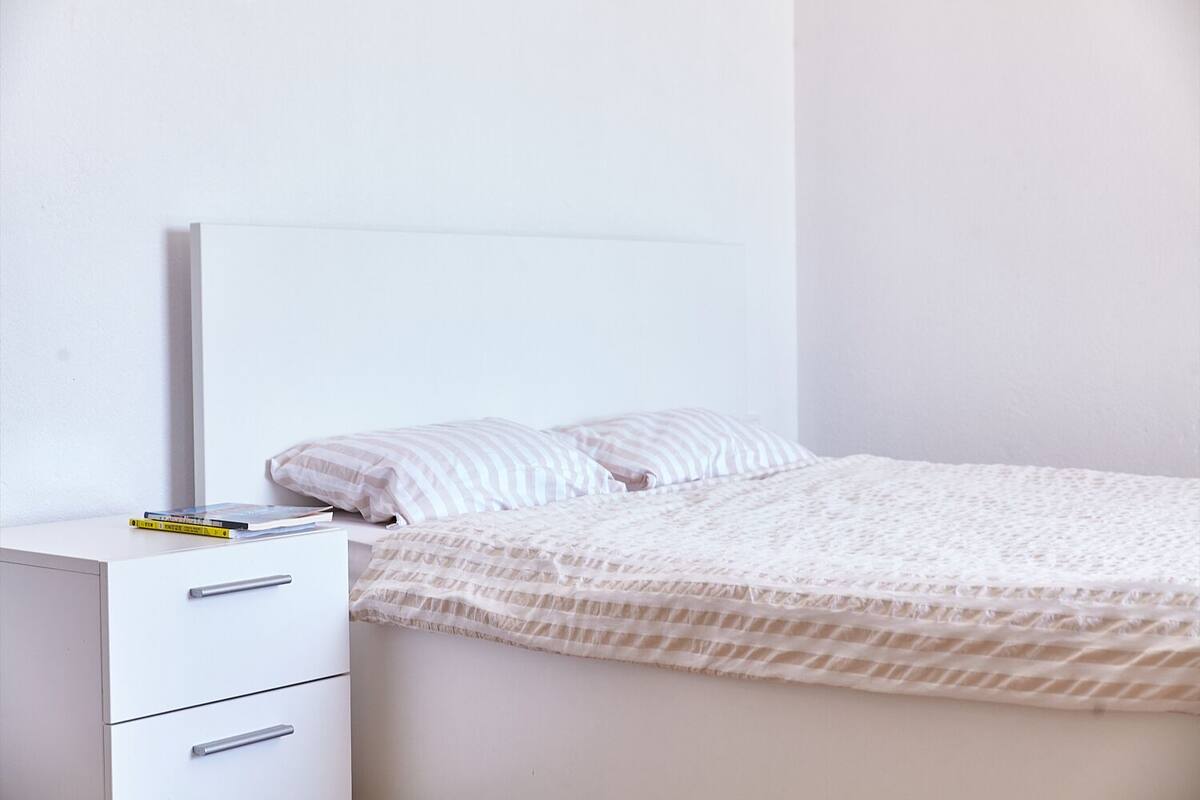 Una camera da letto con un letto, un comodino e una abat-jour.