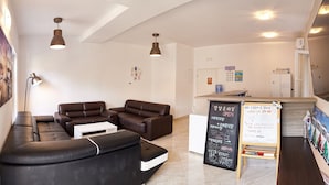 A modern hotel lobby with leather sofas, a reception desk, and a chalkboard with information.