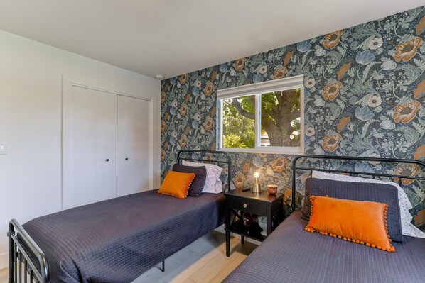 A bedroom with two beds, a window, and a nightstand with a lamp. - ***Carpenter Lane*** (Redding)