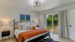 A bedroom with a bed, bedside tables, a window, and a view of the outdoors. - ***Carpenter Lane*** (Redding)