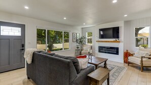 A modern living room with a grey sofa, a wooden coffee table, and a flat-screen TV mounted on the wall. - ***Carpenter Lane*** (Redding)