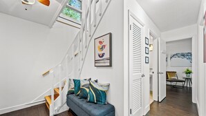 A modern interior with a staircase, a blue sofa with decorative pillows, and a framed artwork on the wall.
