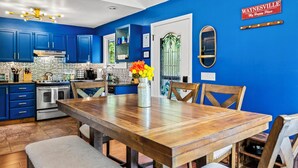A kitchen with blue cabinets, a wooden dining table, and a vase with flowers.