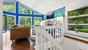 A spacious living room with a large window, a blue accent wall, and a cozy seating area.