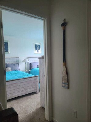 A bedroom with a bed, a nightstand, and a wall-mounted broom. - Sunset Vista Home with POOL (Tuckerton)
