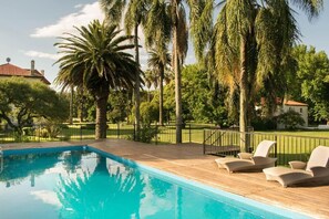 Una piscina con sillas de descanso y palmeras.