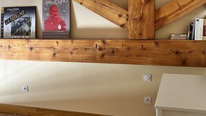 Ein Zimmer mit freiliegenden Holzbalken, einem Bücherregal voller Bücher und einem weißen Schrank.