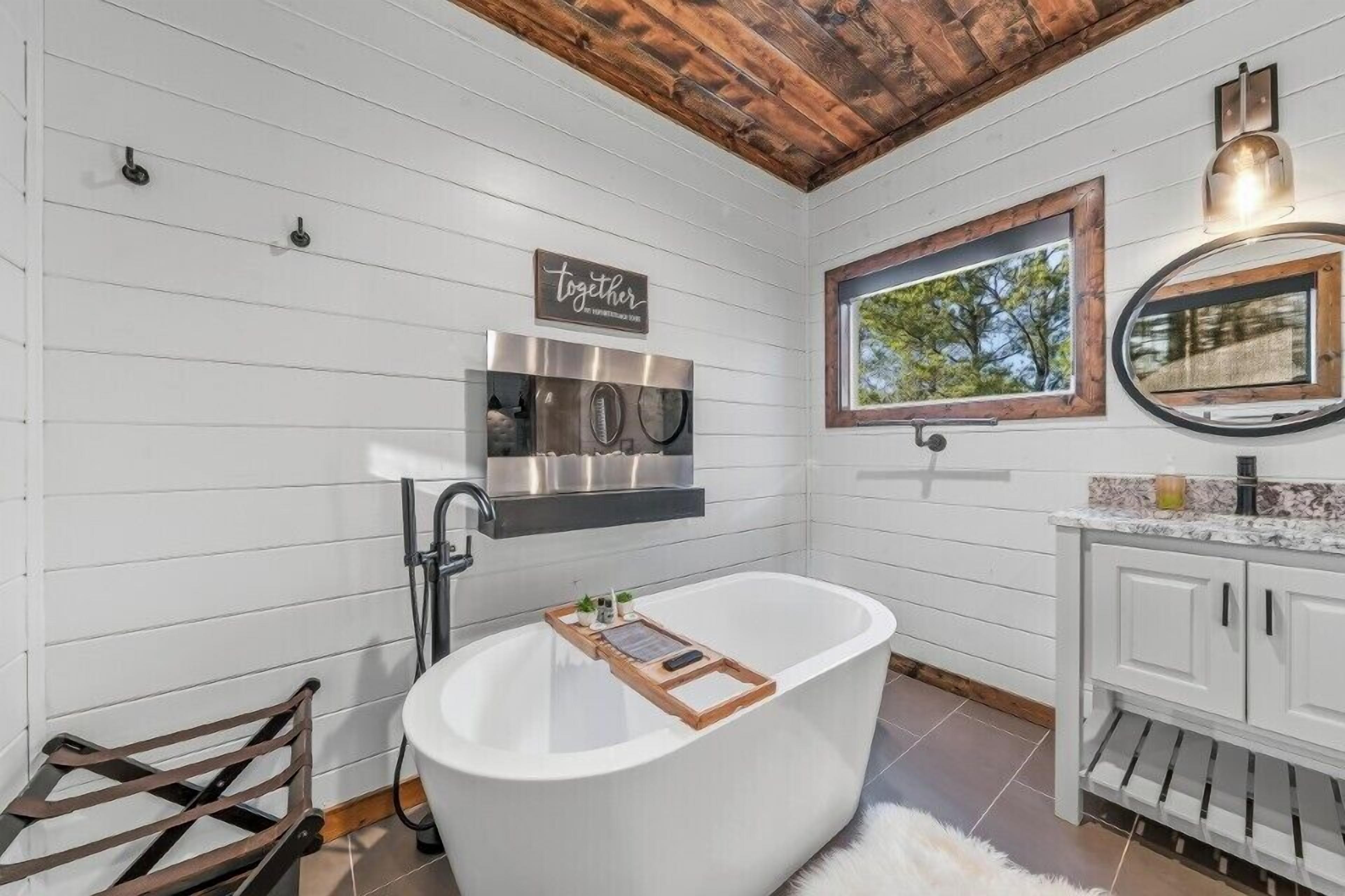 A modern bathroom with a freestanding bathtub, a stainless steel shower, and a vanity with a mirror.